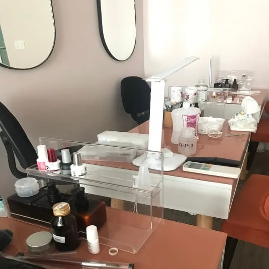 Bàn làm móng trong tiệm nail có kệ mica trong suốt đựng sơn